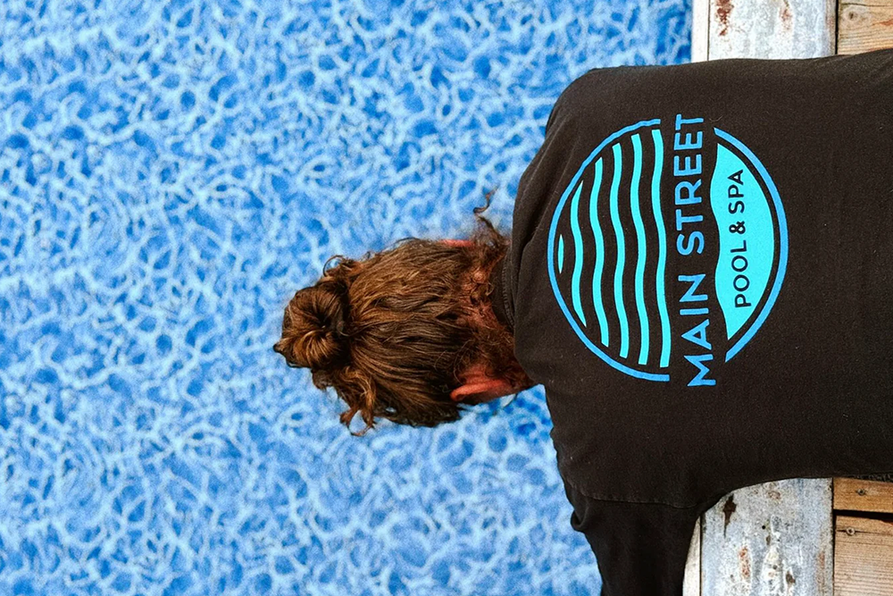 Main Street Pool & Spa technician inspecting a pool, ensuring clean and crystal-clear water with expert maintenance services in Uxbridge.