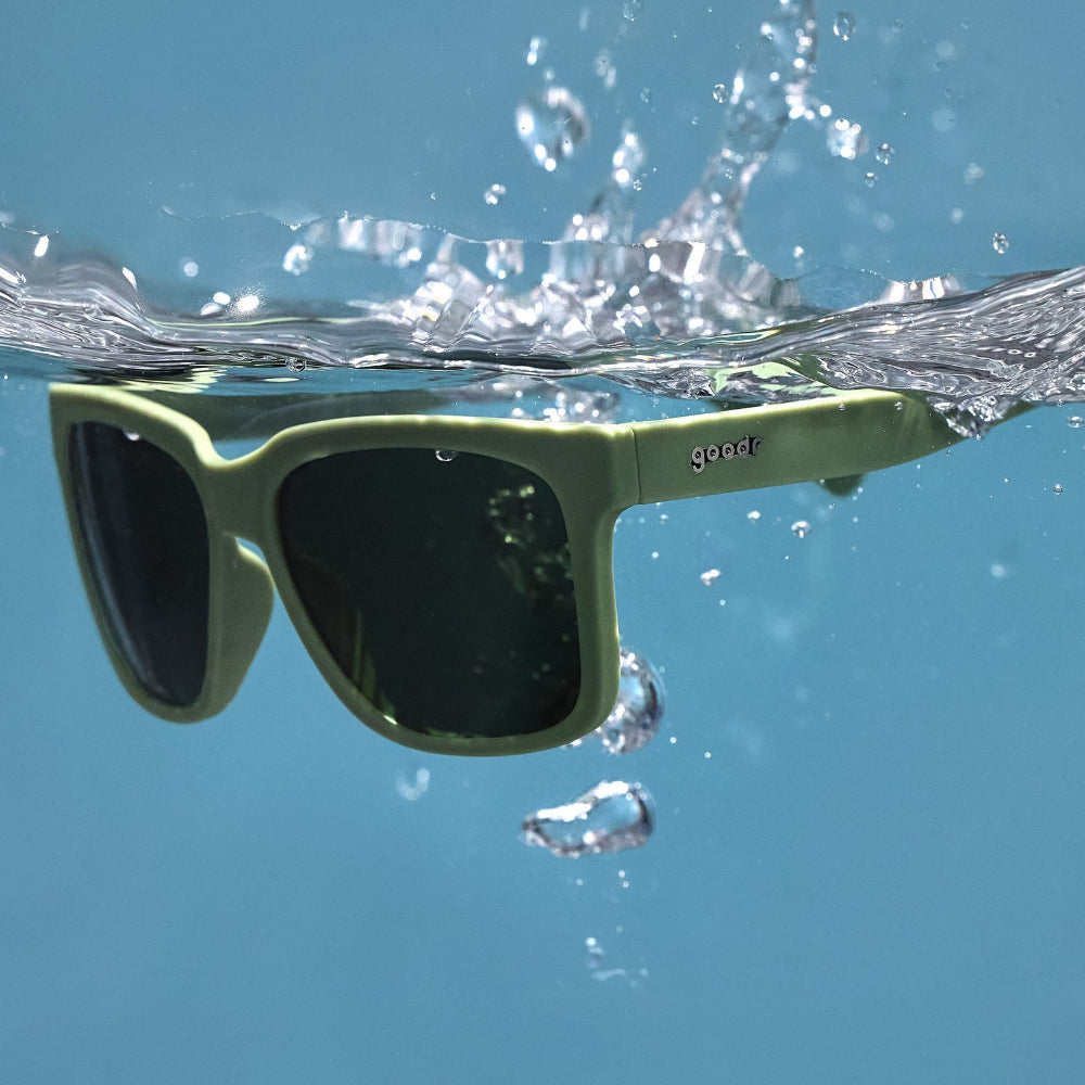 Green sunglasses with black lenses floating on water