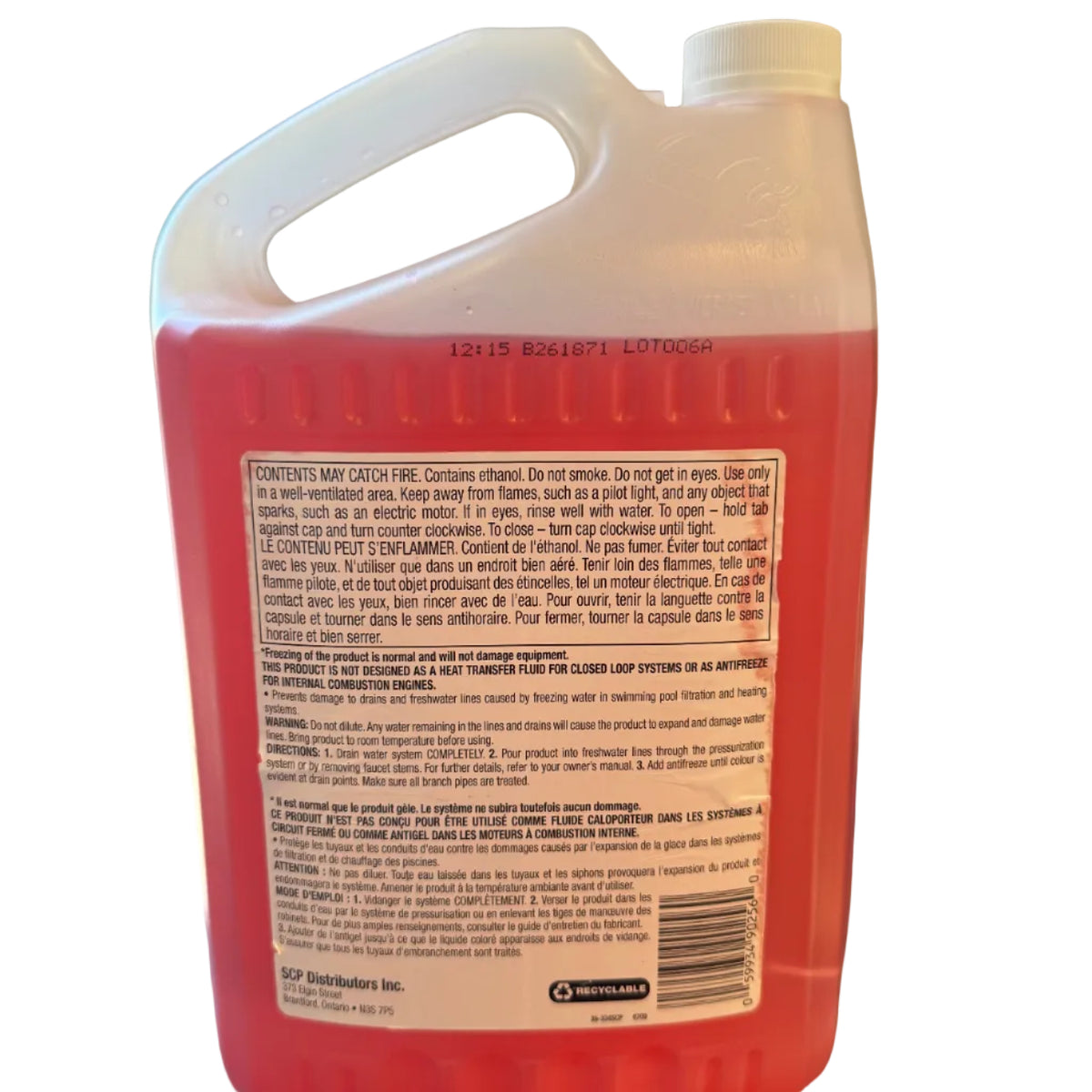 A large plastic jug of red liquid cleaner or solvent with a white handle and cap, photographed from the back to show the printed warning label. The jug is sitting on a dark surface indoors.