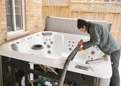 A technician inspecting and draining a hot tub