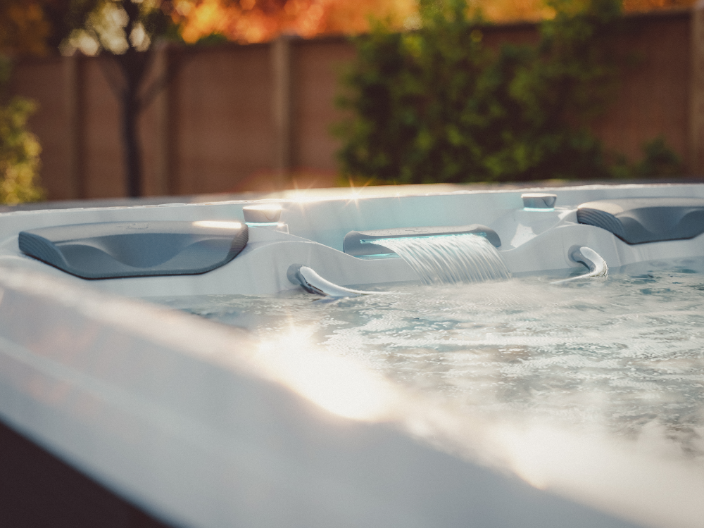 Close-up of the waterfall feature on a Sundance® Surf™ 17 Swim Spa with autumn foliage in the background.