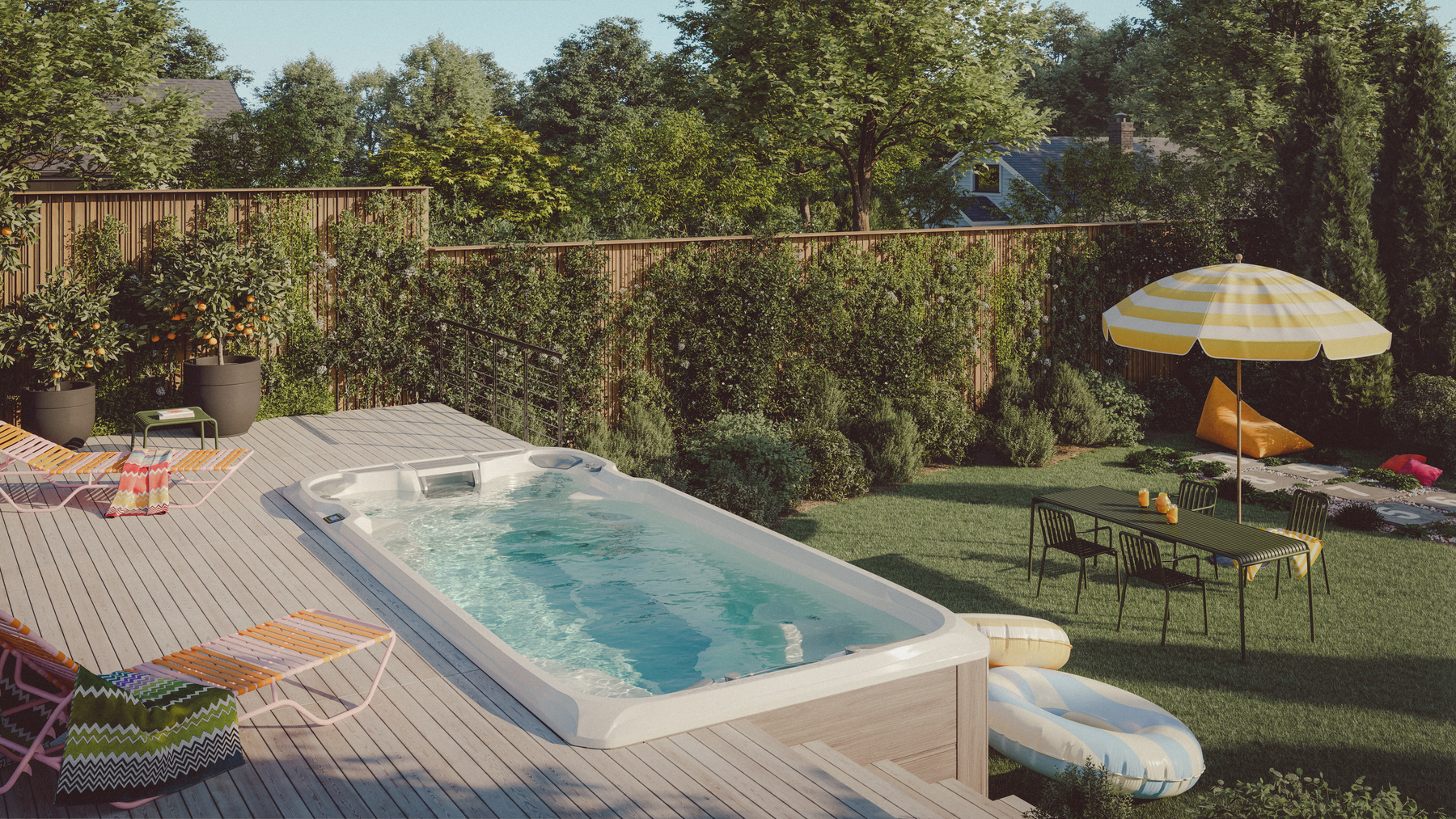 Sundance® Stream™ 17 Swim Spa installed in a landscaped backyard with a wooden deck, colourful lounge chairs, and a dining setup under a yellow-striped umbrella.